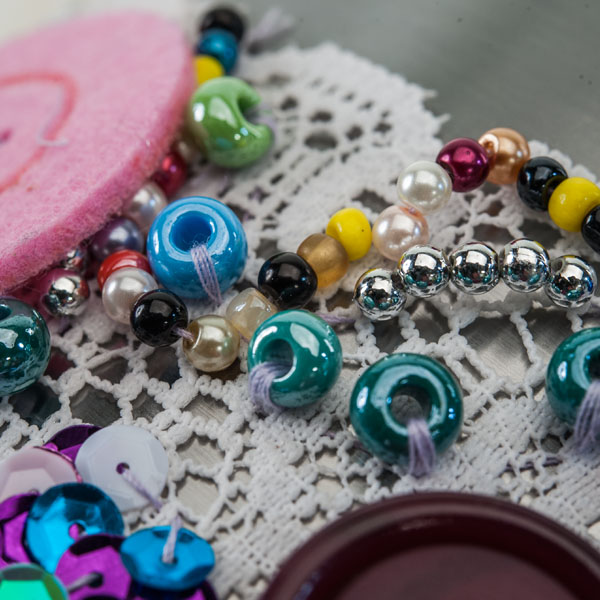 Stahl Urne- Vintage Design Detailaufnahme -Urnenwerk - Individue Nahaufnahme der Details: bestickt mit Perlen auf Spitzenband